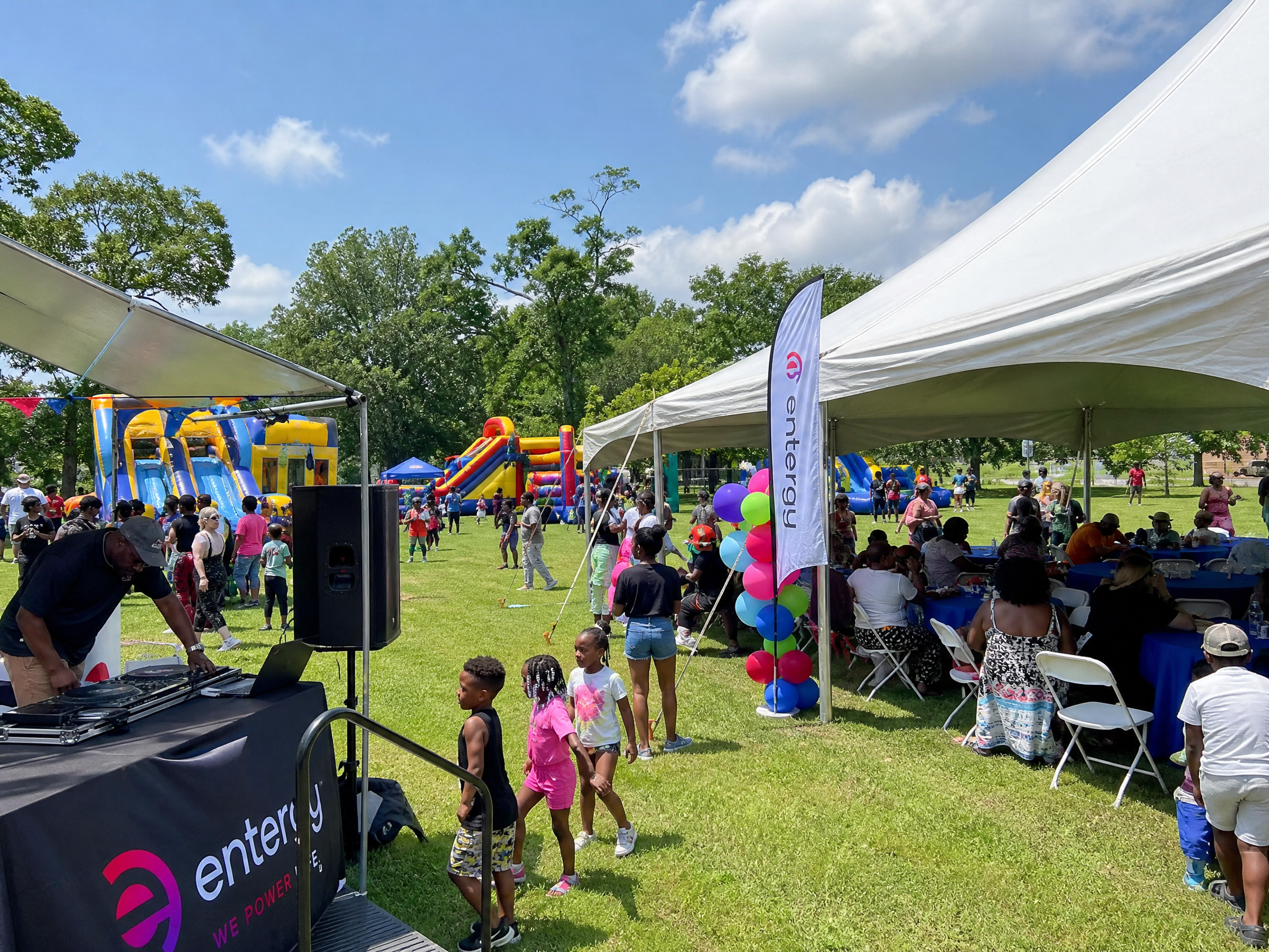 Corporate family day with bounce houses, tents, and DJ in a park setting