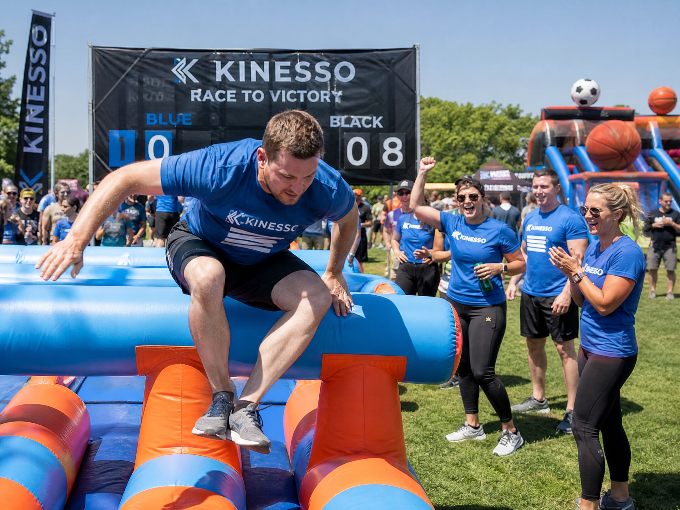 Corporate team building event with adults competing on inflatable obstacle course