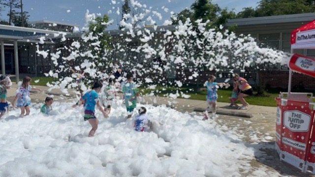 Foam covering the ground near a brick school building during field day