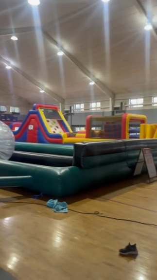 Indoor gym at Christ Episcopal with zorb track and inflatables on hardwood floor